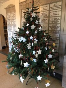 A tree with star-shaped decorations hanging from its branches. The decorations have messages for loved ones written on them.